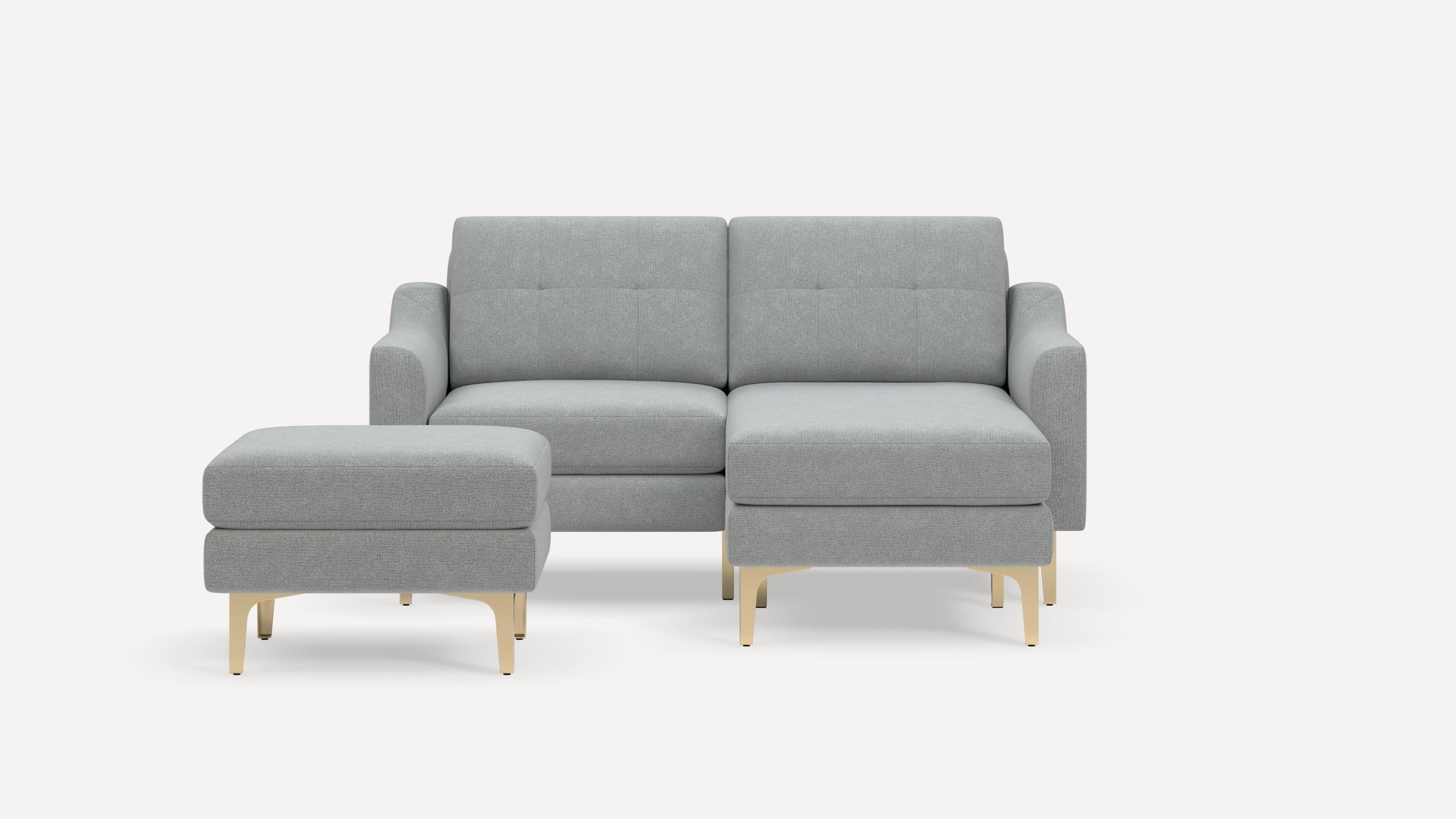 Modern light gray fabric sectional sofa with tufted back cushions and gold metal legs, accompanied by matching ottoman.