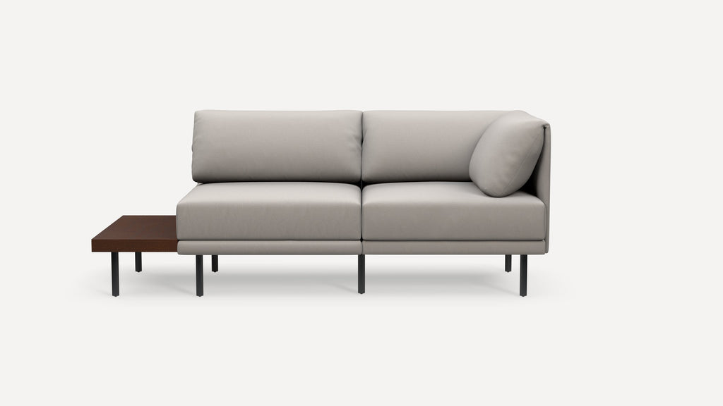 Modern light gray fabric sectional sofa with black metal legs and an integrated dark wood side table on the left side.