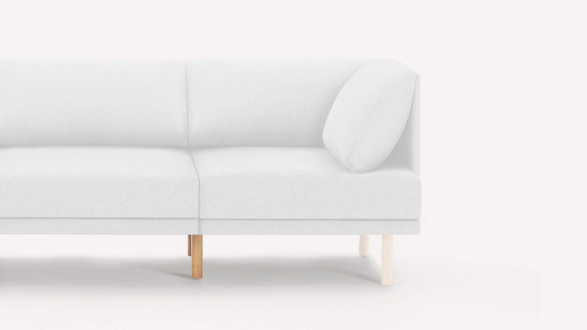 Modern white fabric sofa with wooden legs and a separate white cushion, shown from the right side.