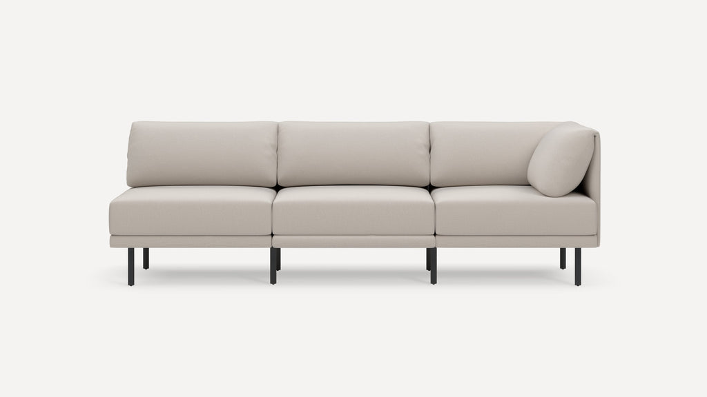 Light beige three-seater modular sofa with clean lines, plush cushions, a single side pillow, and thin black metal legs on a white background.