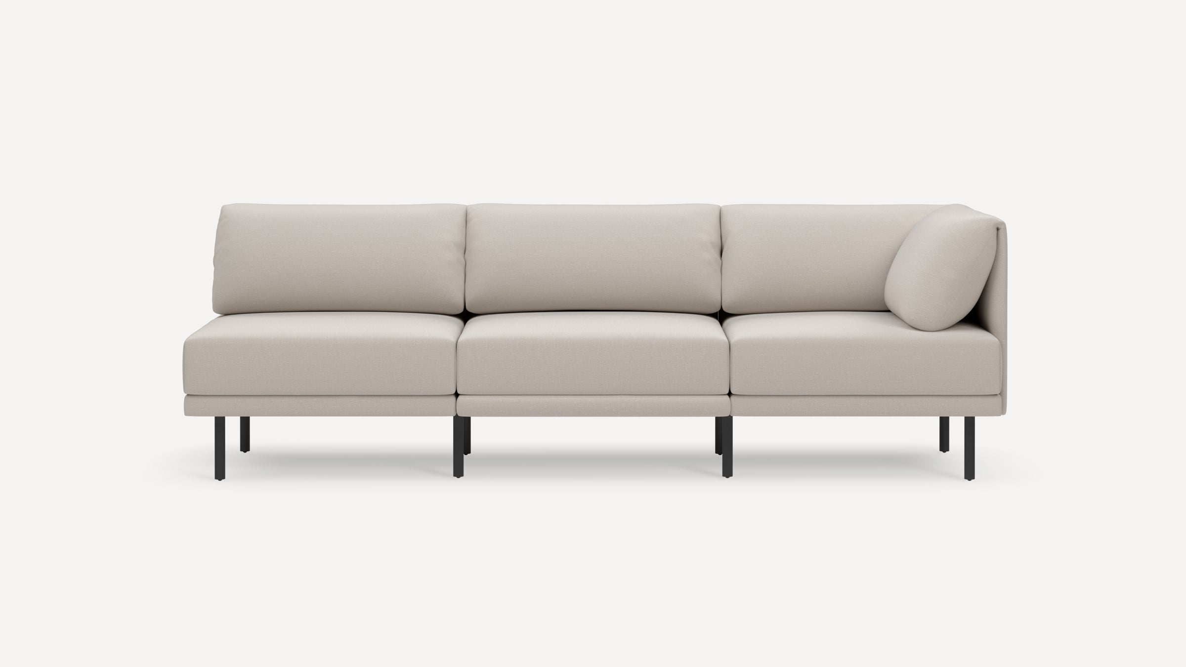Light beige three-seater modular sofa with clean lines, plush cushions, a single side pillow, and thin black metal legs on a white background.