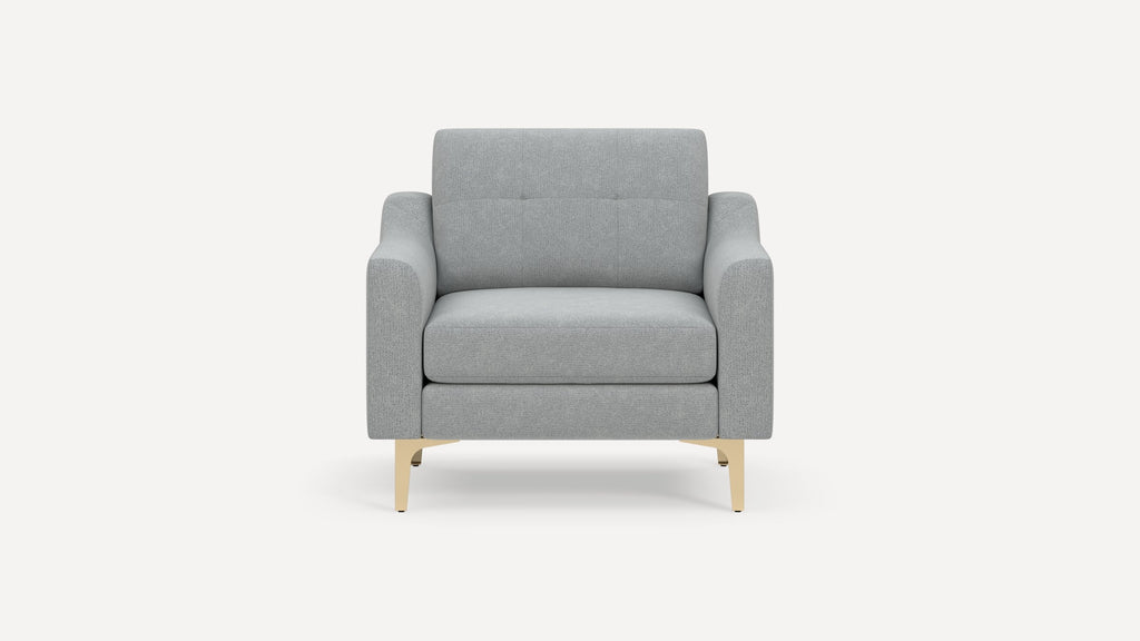 Light gray upholstered armchair with sleek, gold metal legs, rectangular arms, and a cushioned backrest with subtle button detailing.