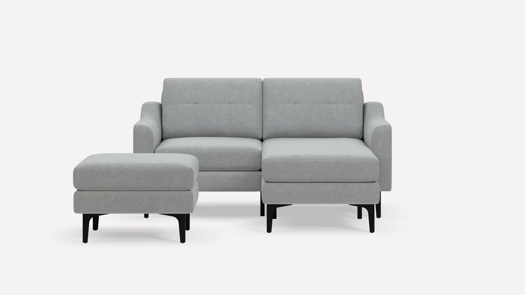 Modern light gray fabric sectional sofa with tufted back cushions and black tapered legs, accompanied by a matching ottoman.