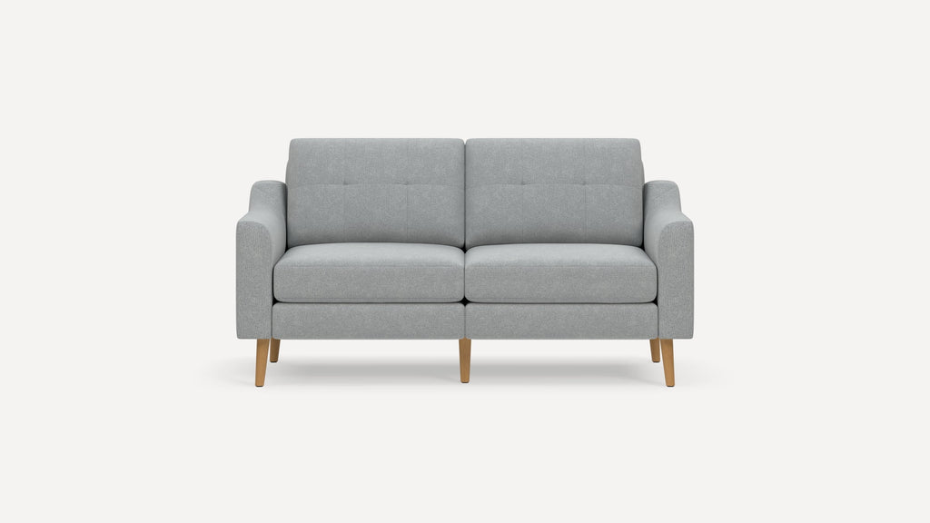 Modern light gray upholstered two-seater sofa with tufted cushions and wooden tapered legs on a white background.
