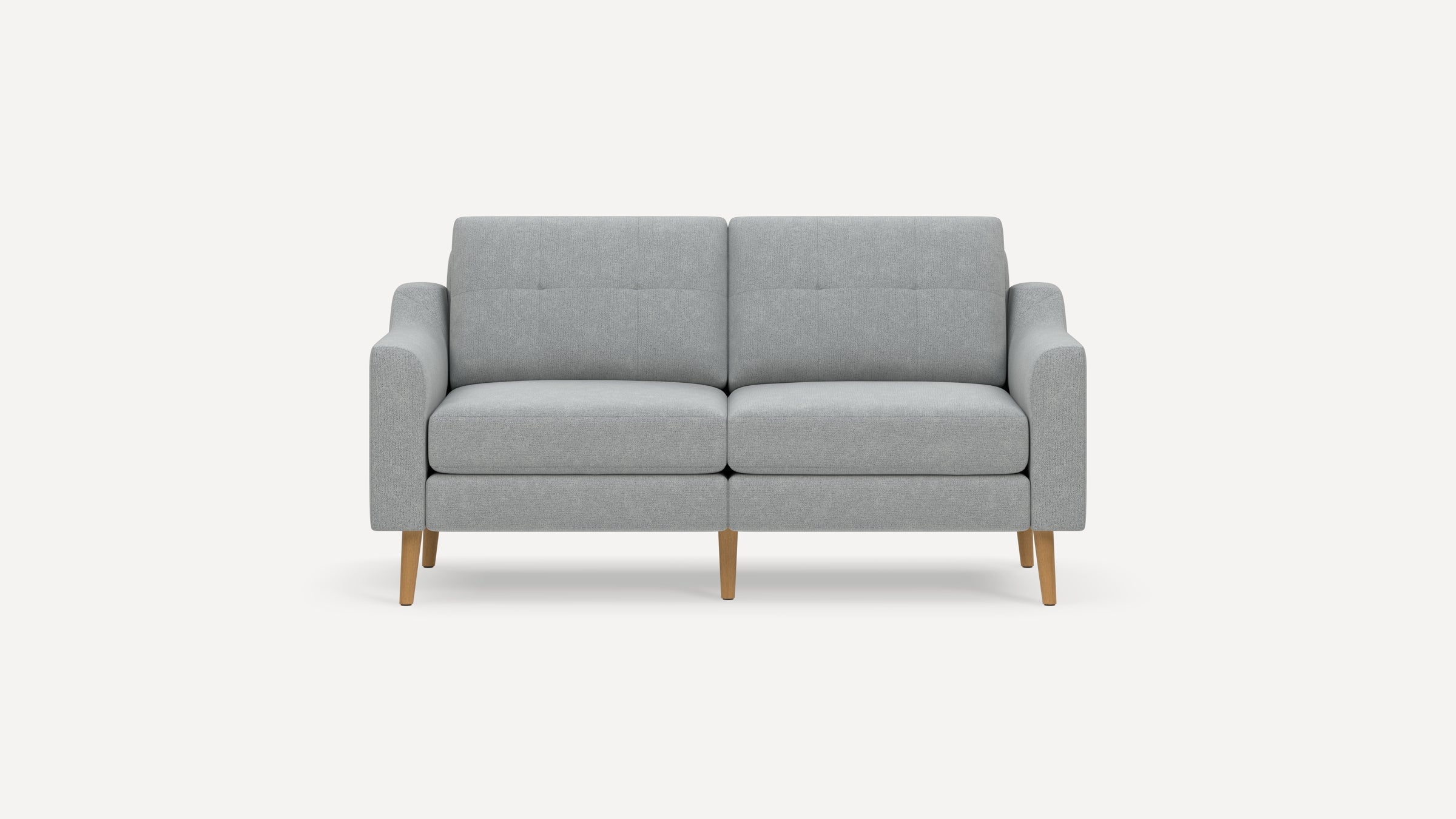 Modern light gray upholstered two-seater sofa with tufted cushions and wooden tapered legs on a white background.