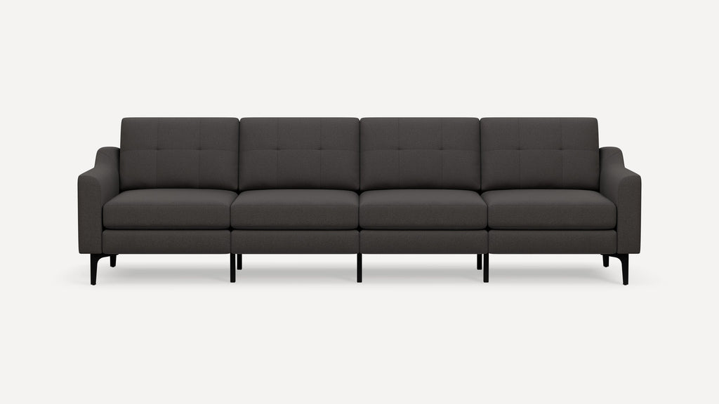 Modern dark gray four-seater sofa with square tufted cushions, upholstered fabric, curved armrests, and black angled legs on white background.