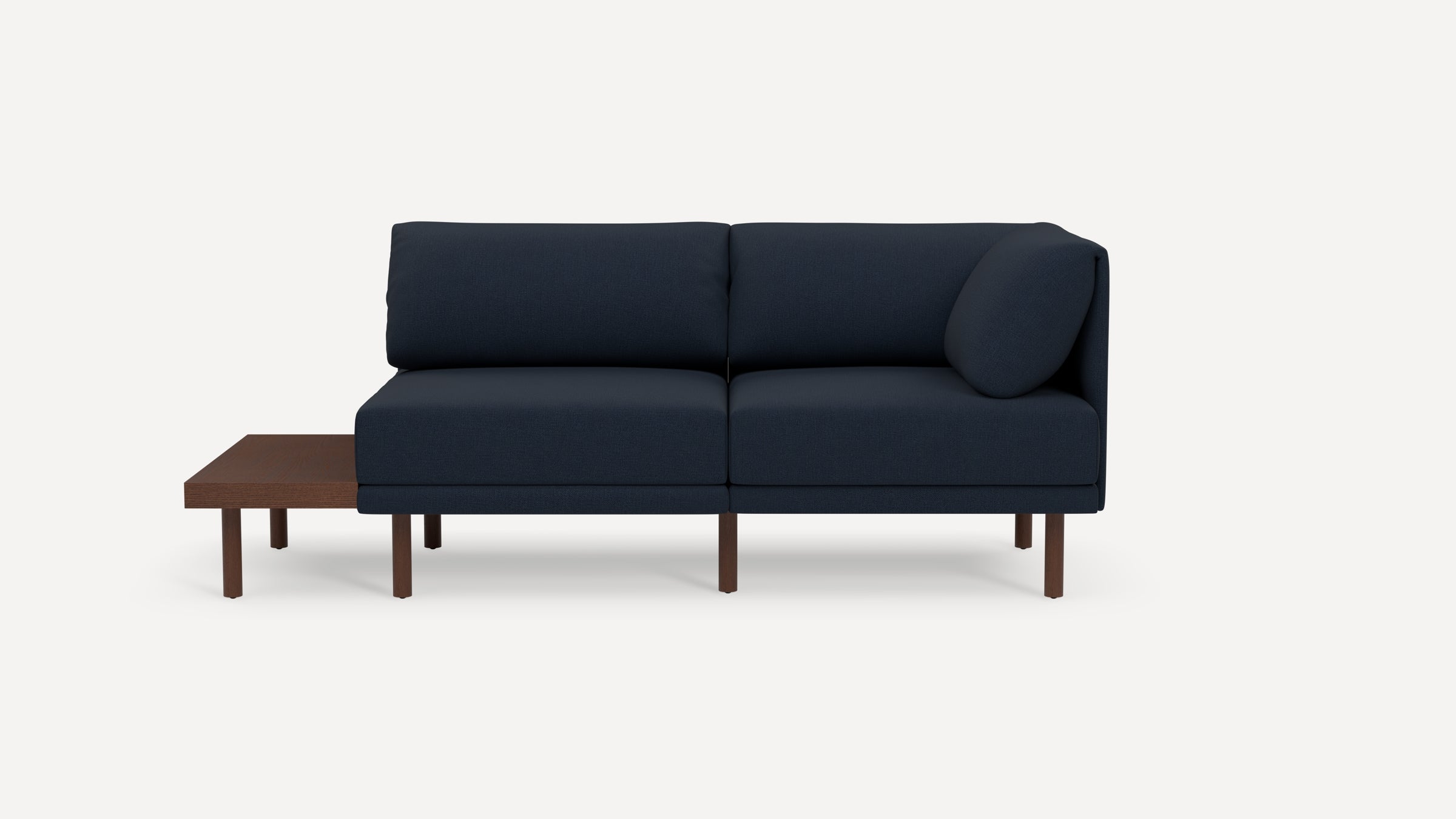 Modern navy blue fabric two-seater sofa with wooden legs and attached dark wood side table on left side.