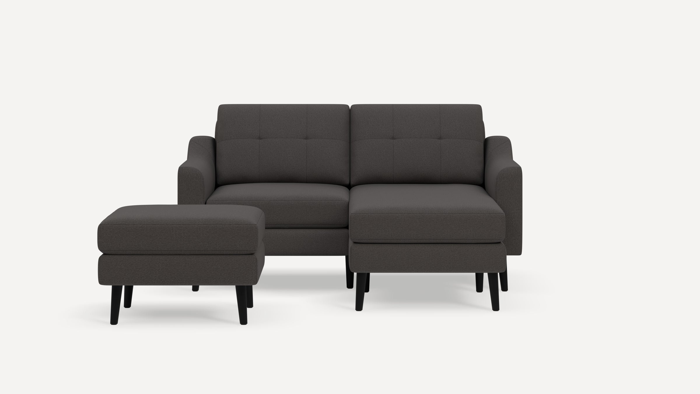 Modern dark gray fabric sectional sofa with tufted back cushions and a separate matching ottoman on black legs.
