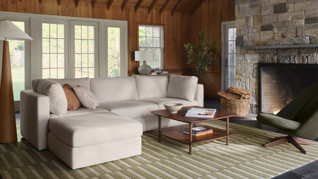 Comfortable tan sofa in cozy living room with wood paneling