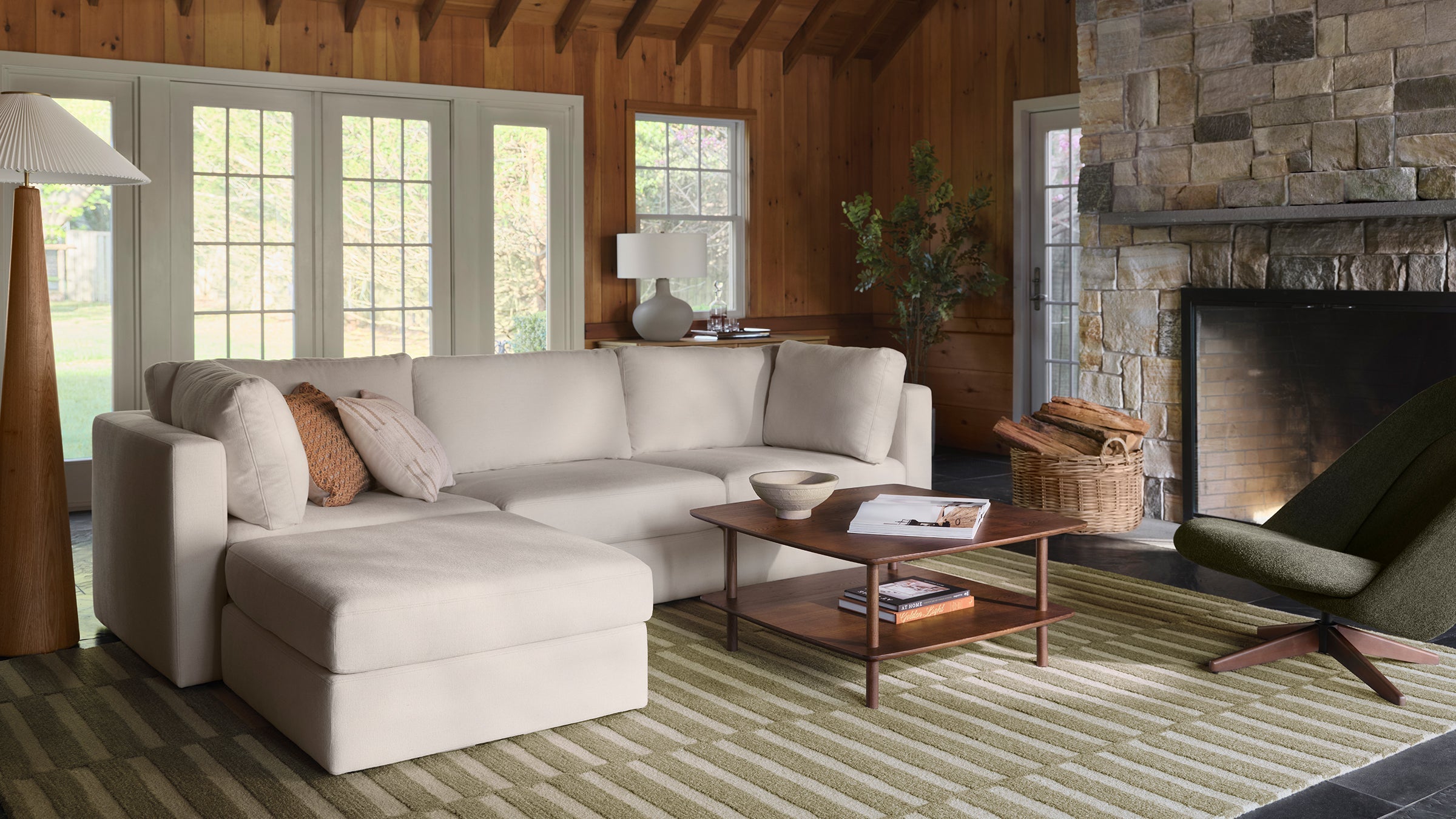 Comfortable tan sofa in cozy living room with wood paneling