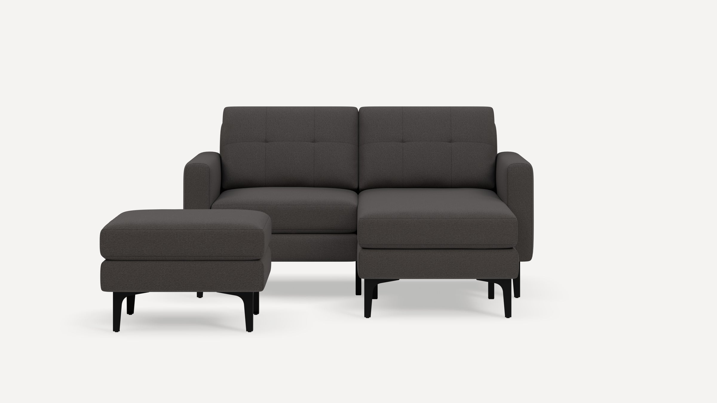Dark grey modern sectional sofa with tufted back cushions and separate matching ottoman on black legs.
