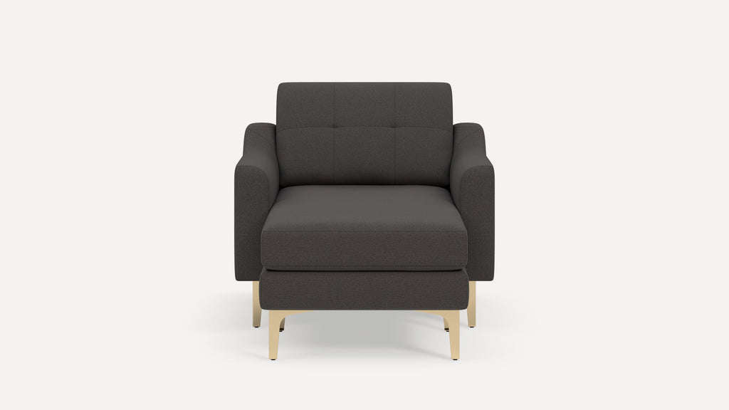 Modern dark gray upholstered armchair with light wood legs, wide cushioned seat, and tufted backrest, viewed from the front.
