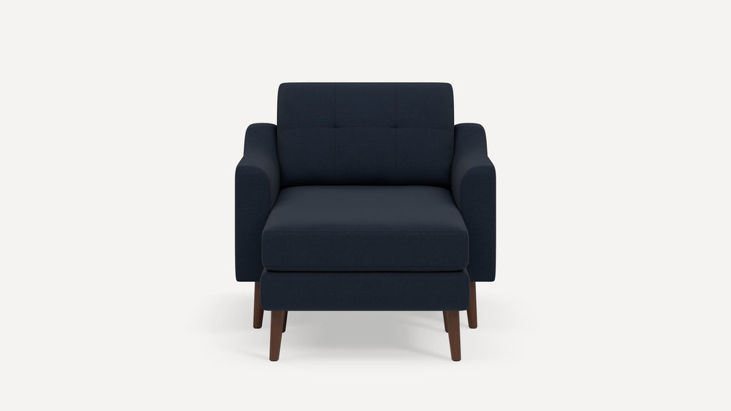Front view of a modern navy blue fabric armchair with tufted backrest and wooden legs on a white background.