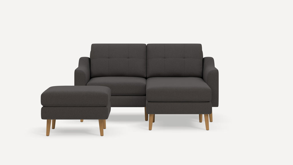 Dark gray modern sectional sofa with tufted back cushions and a matching ottoman, both featuring wooden legs.