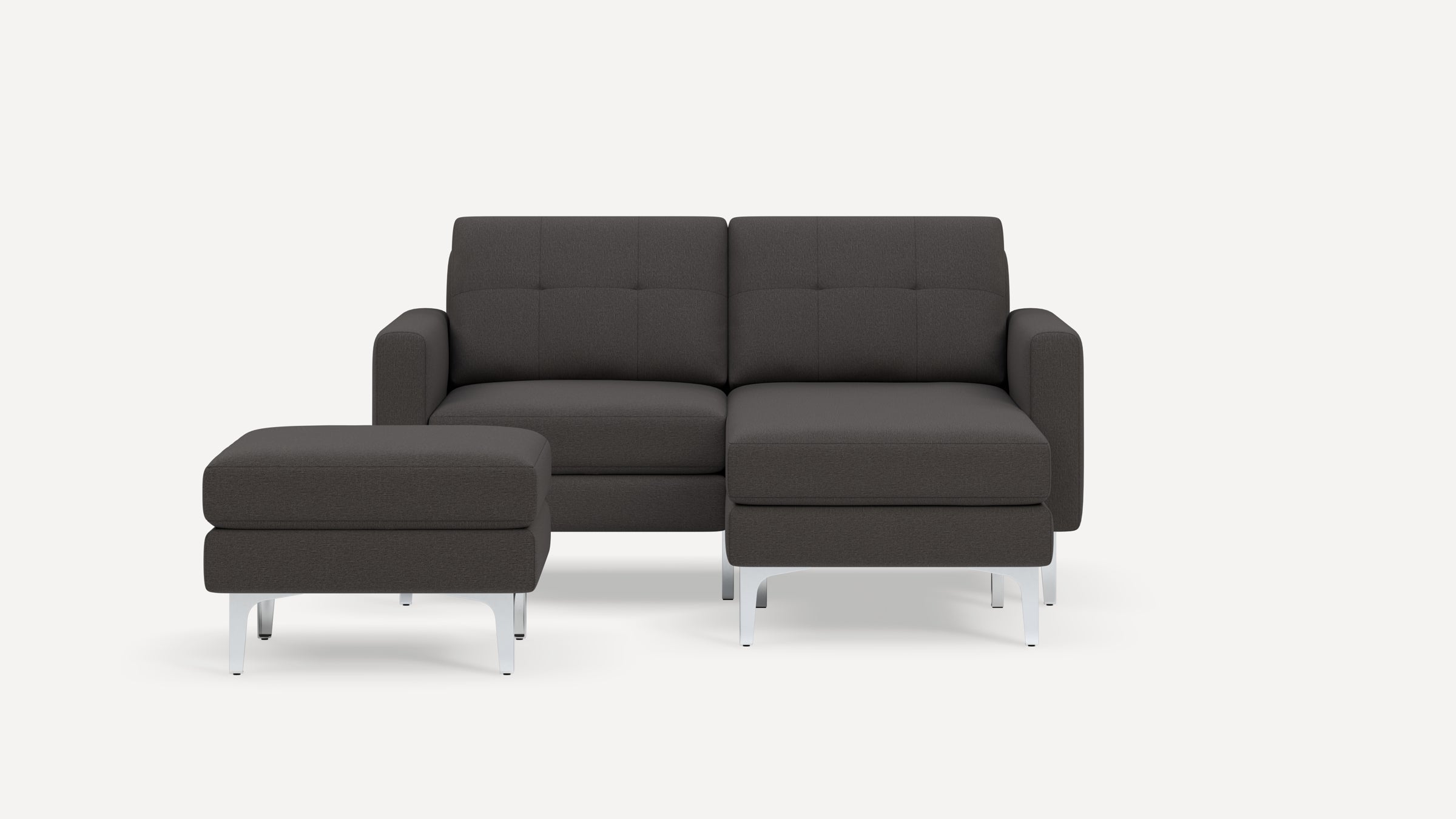 Modern dark gray fabric sectional sofa with tufted back cushions, armrests, and a matching ottoman on angled silver legs.
