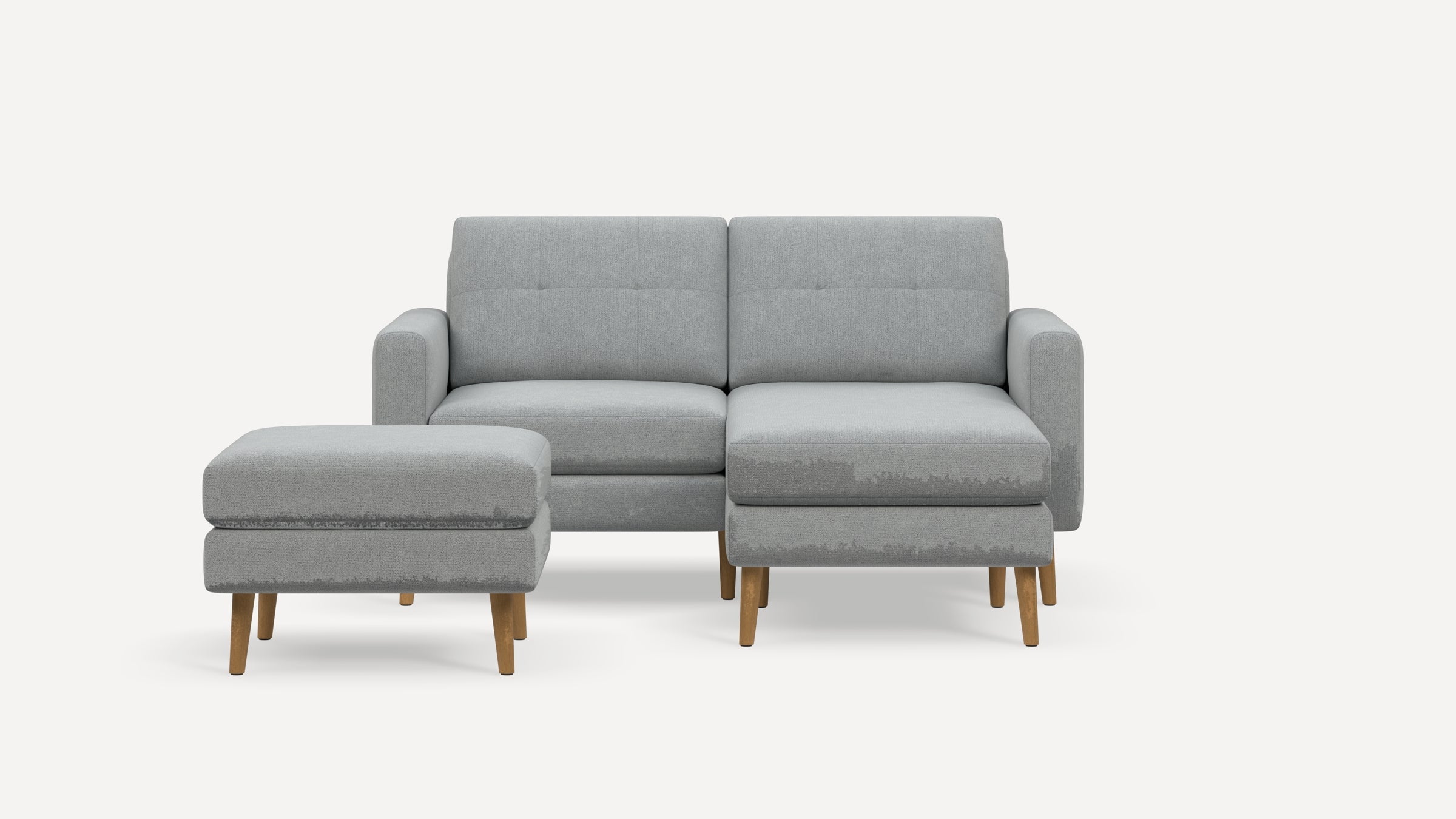 Light gray modern sectional sofa with wooden legs and matching ottoman on a white background.