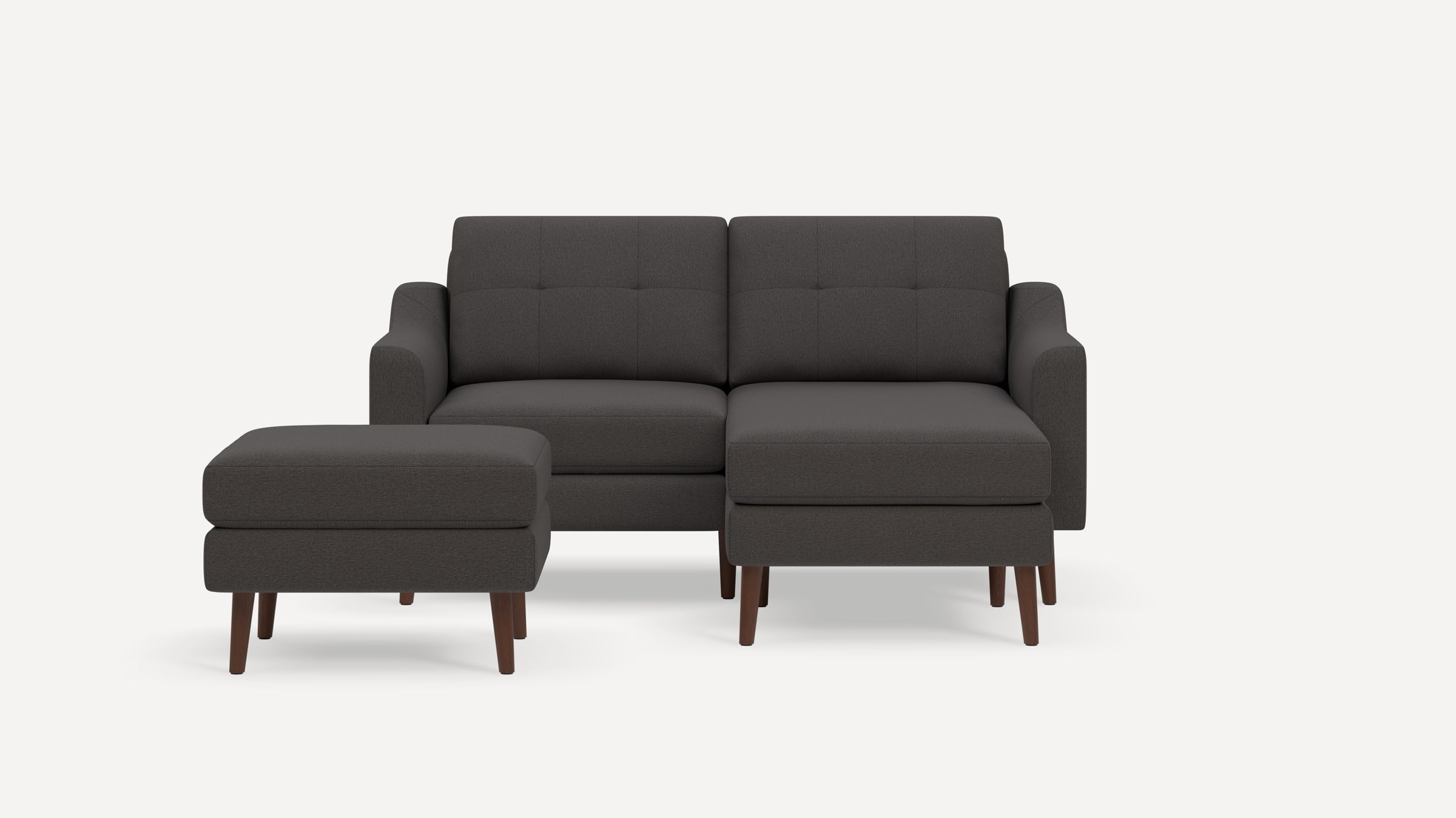 Dark gray fabric sectional sofa with tufted back cushions, wooden legs, and matching ottoman on a white background.