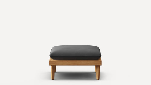 Square wooden ottoman with thick dark gray cushion, minimalist design, four sturdy legs, set against plain white background.