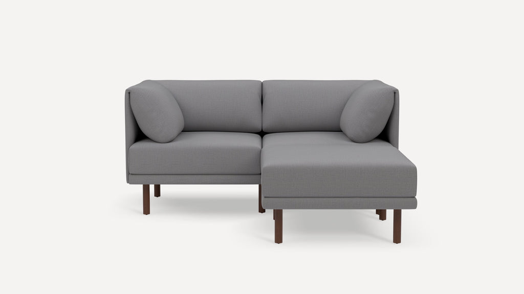 Modern gray L-shaped sectional sofa with wooden legs and rounded cushions on a white background.