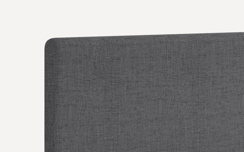 Close-up of dark gray upholstered fabric headboard with rounded top corner and textured weave pattern.