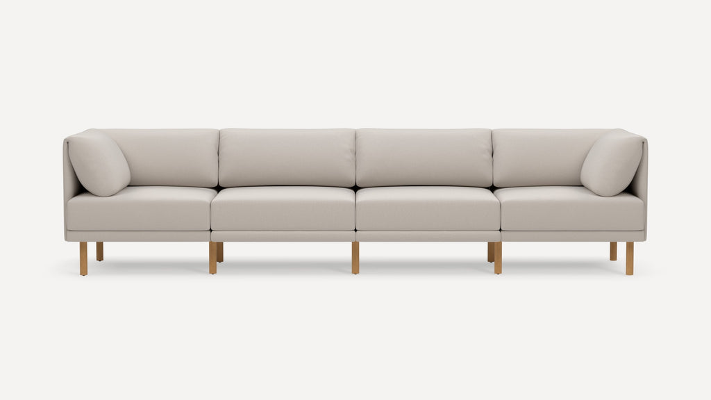 Modern light beige four-seater sofa with wooden legs, featuring square cushions and a minimalist, clean design.